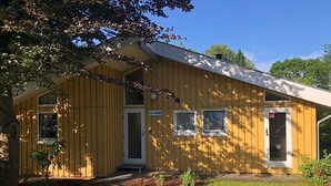 A yellow building with a covered porch, a door, and two windows. - Ferienhaus mit Sauna im Ferienpark Mirow (Mirow)