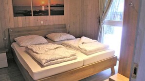 A wooden-paneled bedroom with a bed, pillows, and a nightstand. - Ferienhaus mit Sauna im Ferienpark Mirow (Mirow)