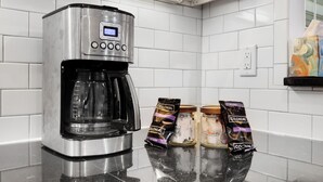 Una cocina moderna con una cafetera, frascos y sobres en la encimera.