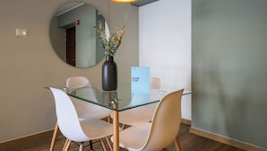 Un comedor moderno con una mesa de vidrio, sillas blancas, un jarrón con flores y un letrero de bienvenida.
