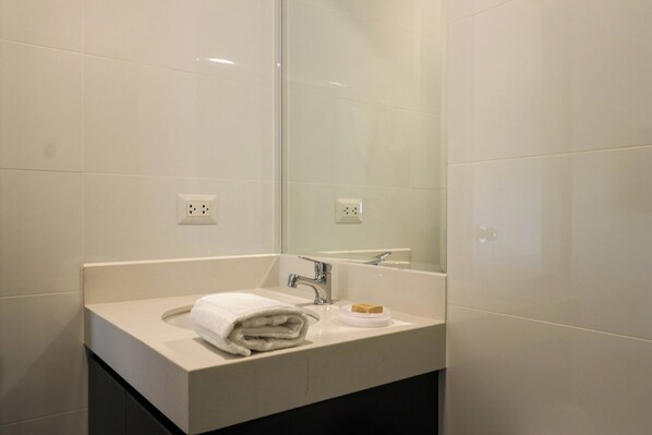 A modern bathroom with a white sink, a mirror, and a towel. - Vital by Wynwood House (Lima)