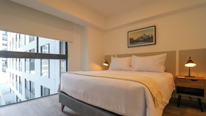 Habitación de hotel moderna con una cama grande, un balcón con vistas a la ciudad y un cuadro en la pared.