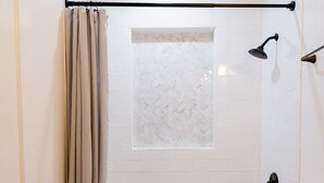 A bathroom with a bathtub, toilet, and a window with a frosted glass panel. - Goldenrod - Studio in Downtown Lexington (Lexington)
