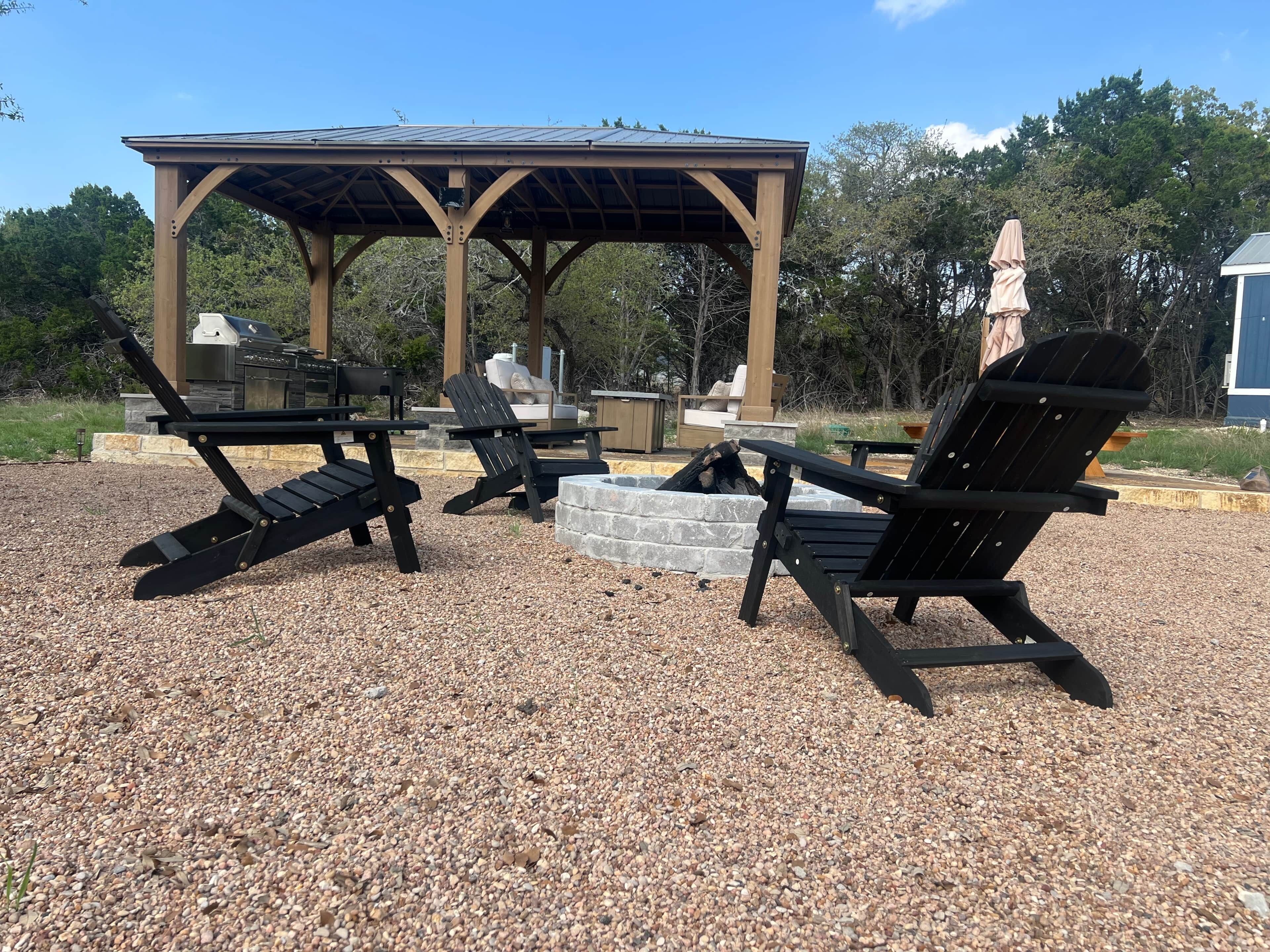 A gazebo with a stone fire pit and outdoor seating.