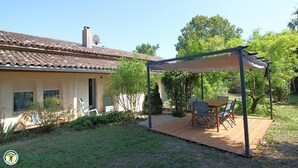 A house with a tiled roof, a covered patio with a table and chairs, and a garden area. - Domaine des 3 Rivières. A haven of peace close to St-Émilion Charente Dordogne. (Guitres)