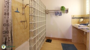 A bathroom with a shower, a towel rack, a small shelf with a plant, and a sink with a mirror. - Domaine des 3 Rivières. A haven of peace close to St-Émilion Charente Dordogne. (Guitres)