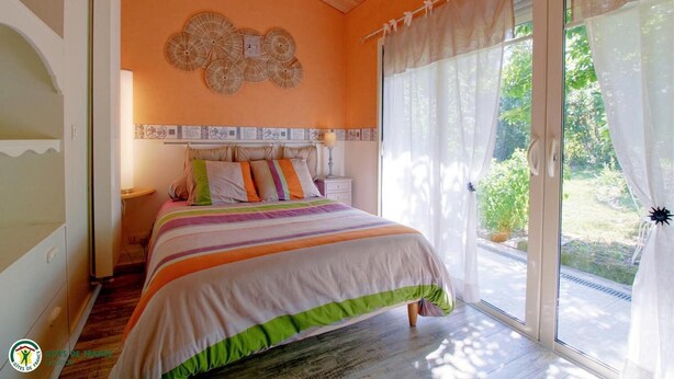 A bedroom with a bed, a nightstand, a wall clock, and a window with curtains. - Domaine des 3 Rivières. A haven of peace close to St-Émilion Charente Dordogne. (Guitres)