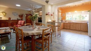 A spacious kitchen with wooden cabinets, a dining area with a round table and chairs, and a living room with a sofa and decorative plants. - Domaine des 3 Rivières. A haven of peace close to St-Émilion Charente Dordogne. (Guitres)