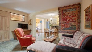 A living room with a sofa, armchair, and dining table. There is a kitchen in the background. - Domaine des 3 Rivières. A haven of peace close to St-Émilion Charente Dordogne. (Guitres)