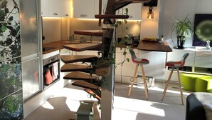 Een moderne keuken met een houten spiraaltrap, witte kasten en een groene stoel.
