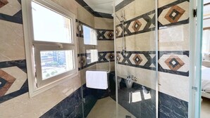 A modern bathroom with a glass shower enclosure, a sink, and a window providing natural light. - Spacious 4-bedroom apartment with WiFi, AC in fantastic Giza Governorate (Giza Governorate)