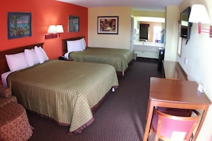 Two single beds with green patterned bedspreads and white pillows, a wooden headboard, and a wall-mounted television.