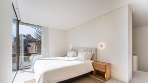 A modern bedroom with a large bed, a nightstand, and a glass door leading to an outdoor area. - GuestReady - DPV GuestHouse - Apart 6 (Porto)