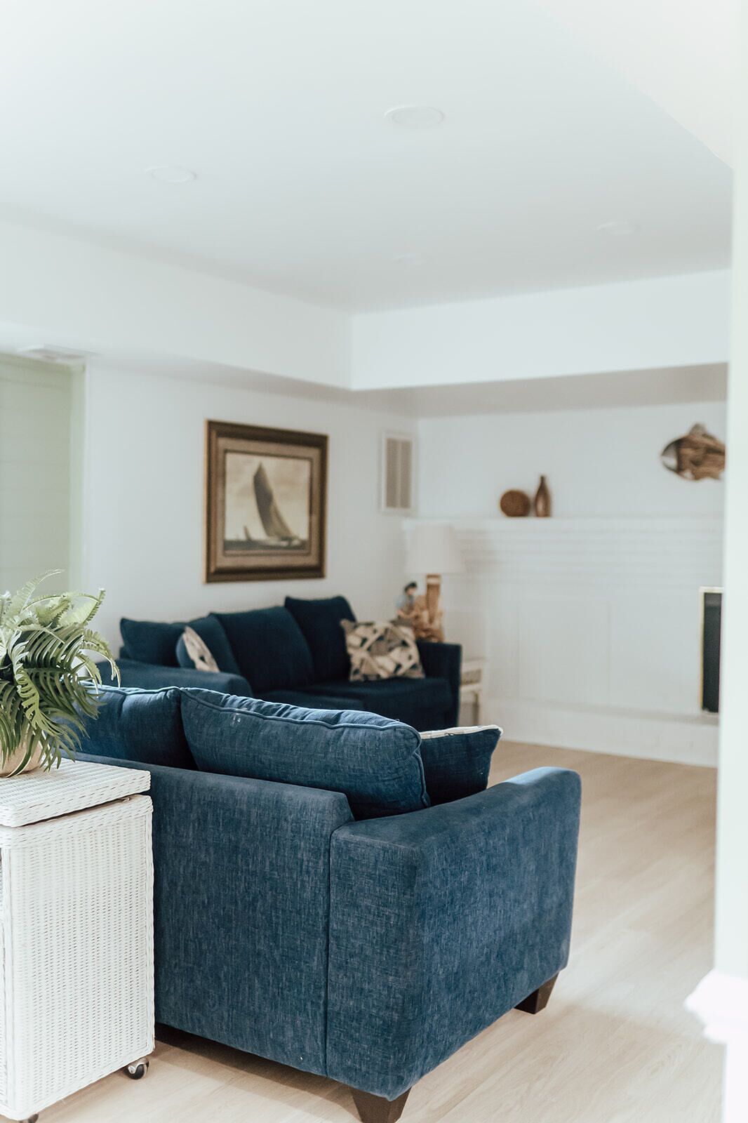 Un salon moderne avec un canapé bleu, une table d’appoint blanche et un tableau encadré accroché au mur.