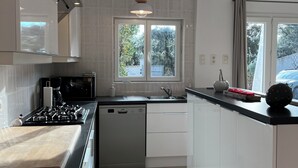 Cozinha moderna com fogão a gás, máquina de lavar louça e janela com vista para o verde.
