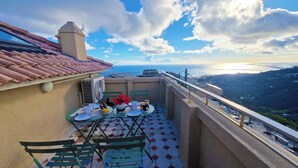 A balcony with a table set for two, a chair, and a view of the sea. - Sublime ROOFTOP sea and mountain view on the heights of Bastia (Ville-di-Pietrabugno)