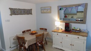 A dining area with a table set for four, a coffee maker, and a cabinet with drawers.