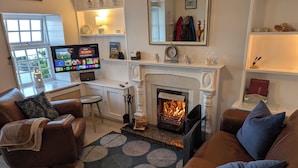 A cozy living room with leather sofas, a fireplace, a television, and a window with a view.