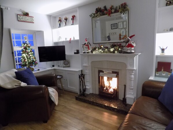 A cozy living room with a fireplace, a television, and a Christmas tree. - Widows Row Cottage, Historic Harbour Property, Panoramic Sea Views, DOG Friendly (Newcastle)