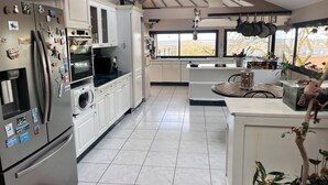 Una cocina moderna con armarios blancos, electrodomésticos de acero inoxidable y un amplio ventanal con vistas al exterior.