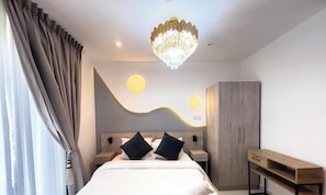 A modern hotel room with a bed, bedside tables, a wardrobe, and a chandelier.