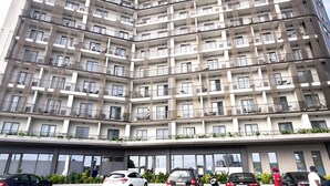 Um edifício residencial com vários andares, varandas, área de estacionamento e céu claro.