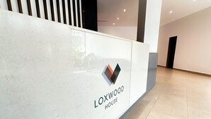 Uma receção com design moderno, apresentando um logótipo e o nome 'LOXWOOD HOUSE'.
