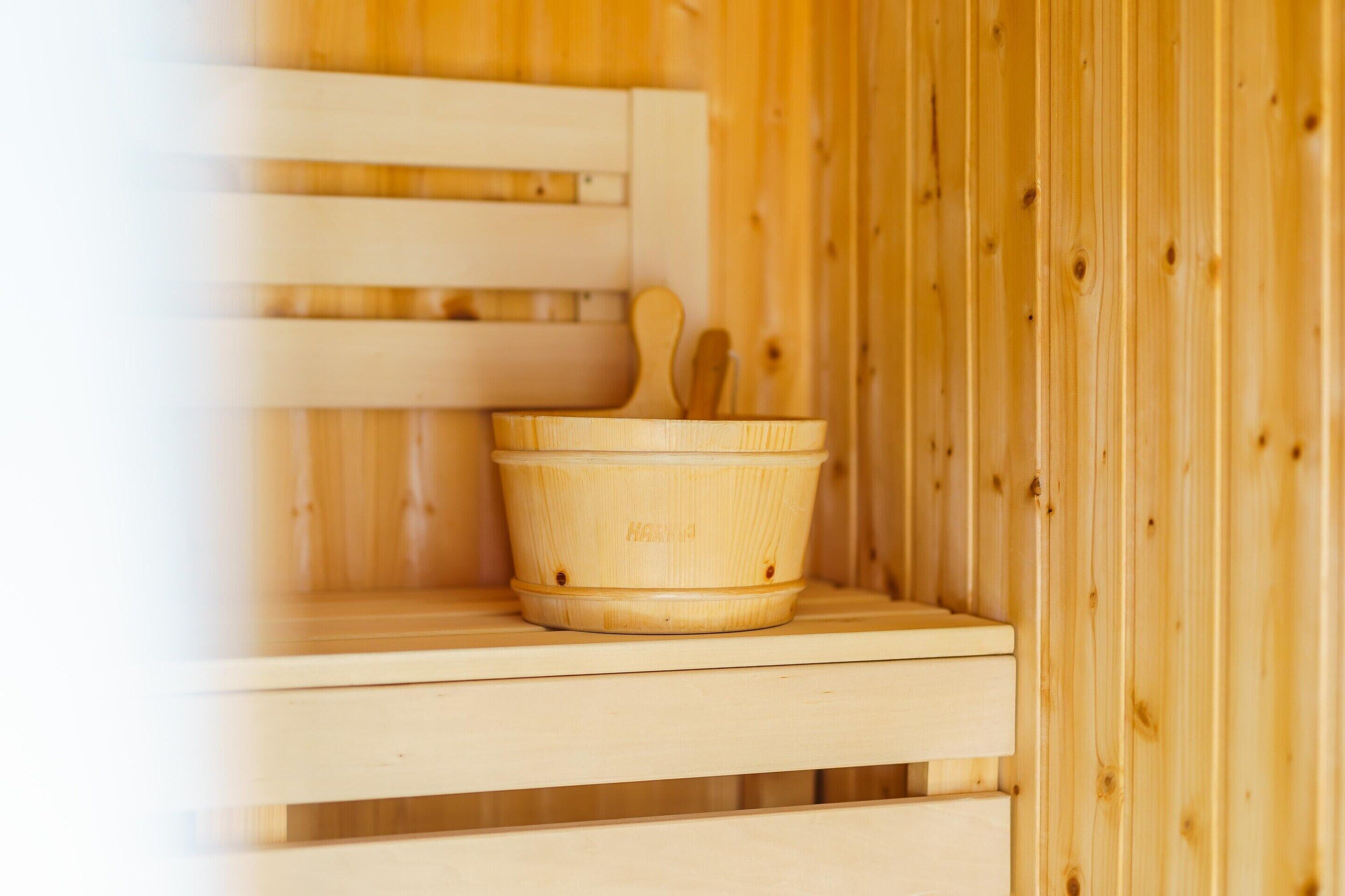A wooden sauna with a wooden bucket and wooden mallets on a shelf.