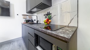A modern kitchen with a marble backsplash, a built-in oven, and a fruit bowl on the counter. - Studio 2 - Gorgeous Studio in Earls Court (London)