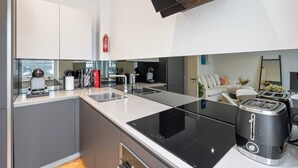 Una cocina moderna con una placa de inducción negra, horno empotrado y una cafetera.
