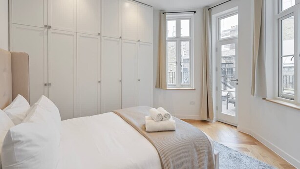 Un dormitorio con una cama, un armario y una ventana con vistas al exterior.