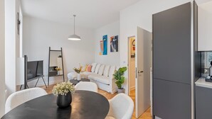 Una sala moderna con una mesa redonda, un sofá blanco y un armario gris.