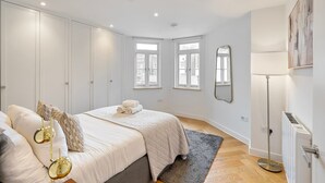 Une chambre à coucher avec un lit, des tables de chevet, un radiateur et une fenêtre.