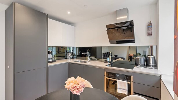 Une cuisine moderne avec des meubles gris, un îlot central et des appareils électroménagers en acier inoxydable.