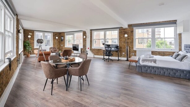 Amplia habitación con zona de comedor, espacio para trabajar y cama.
