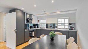 Una cocina moderna con comedor, que incluye una mesa grande, sillas y una planta en maceta.