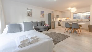 Ein modernes Hotelzimmer mit Bett, Sofa, Essbereich und Küchenzeile.