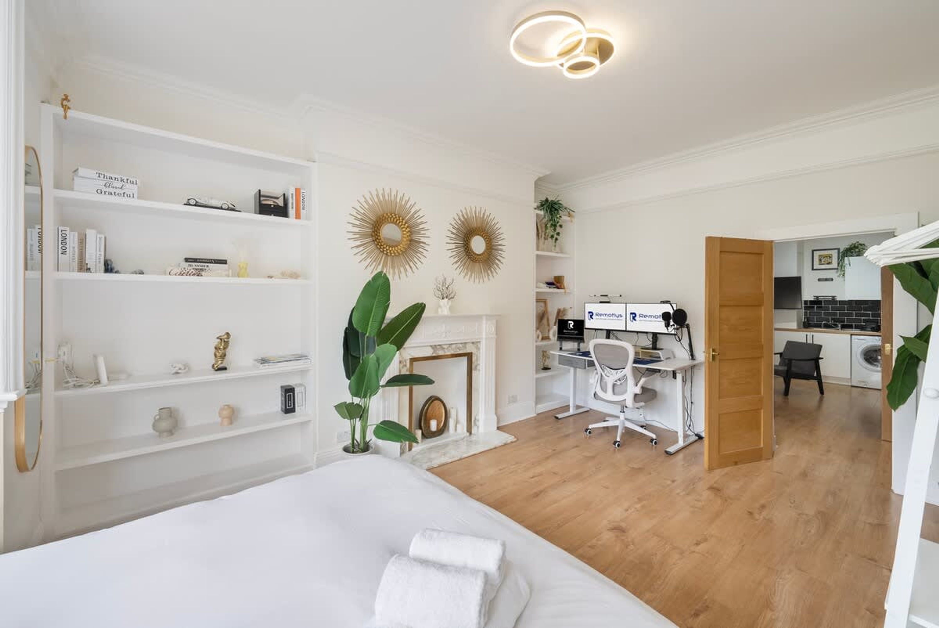 A bedroom with a bed, a desk, and a fireplace.