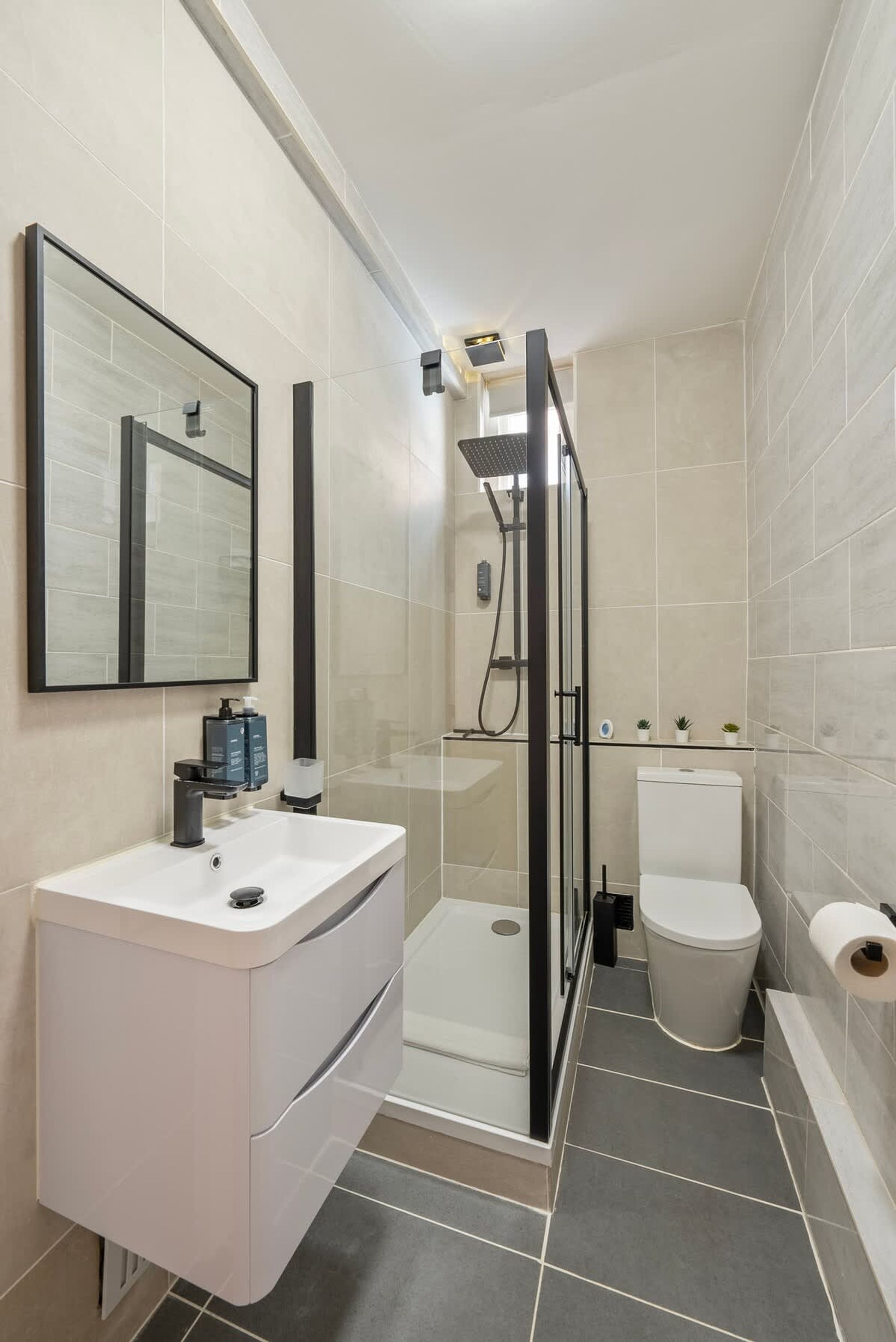 A modern bathroom with a shower, toilet, and sink.
