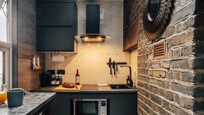 A compact kitchen with a built-in microwave, a coffee machine, and a bread loaf on the counter. - Studio 1 - Charming Studio in Earls Court (London)