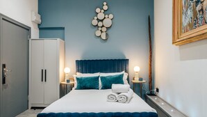 A bedroom with a bed, bedside tables, a wardrobe, and a wall art piece. - Studio 1 - Charming Studio in Earls Court (London)