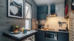 A modern kitchen with dark cabinetry, a built-in oven, and a marble countertop. - Studio 1 - Charming Studio in Earls Court (London)
