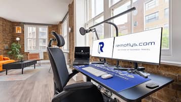 Oficina moderna con escritorio, computadora y silla. Se ve una ventana con vistas a edificios.