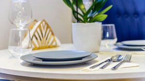 Une table à manger dressée avec des assiettes, des couverts et un verre.
