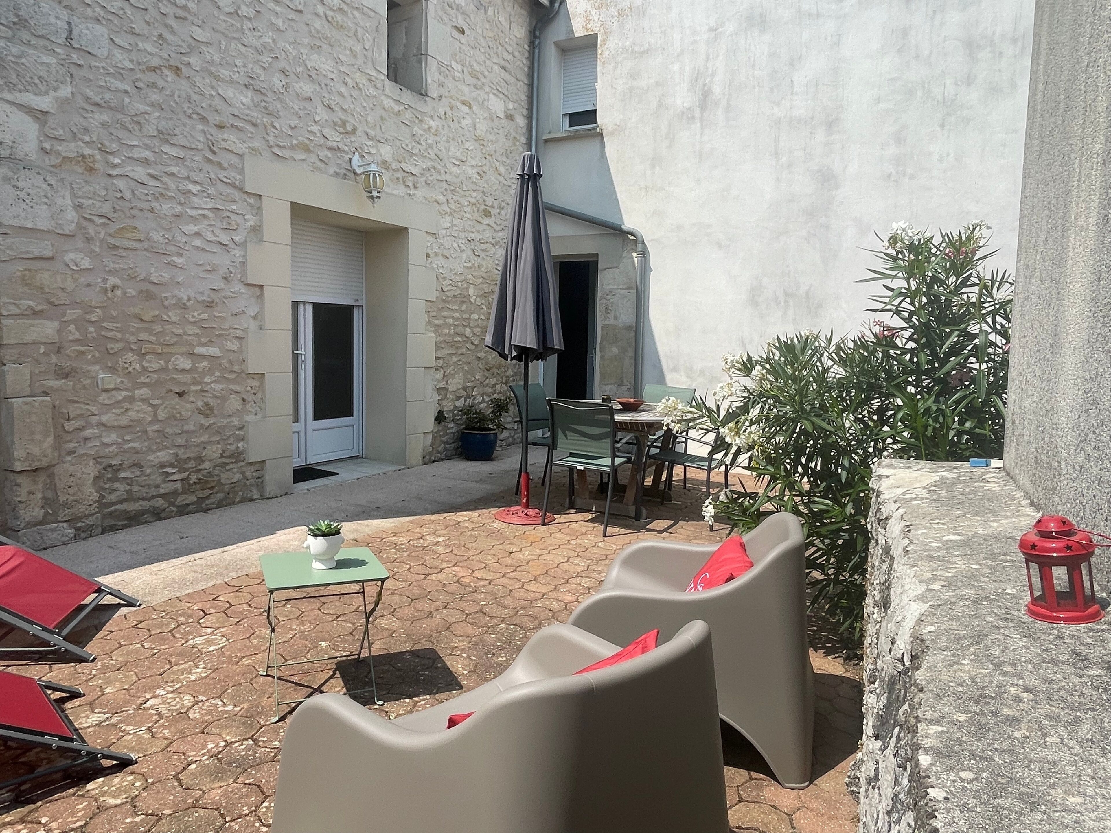 A courtyard with outdoor seating, a table, chairs, and a potted plant.