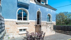 A patio with a stone wall, a blue building, and a staircase leading to a balcony. - Ti an dour, entre terre et mer (Crac'h)