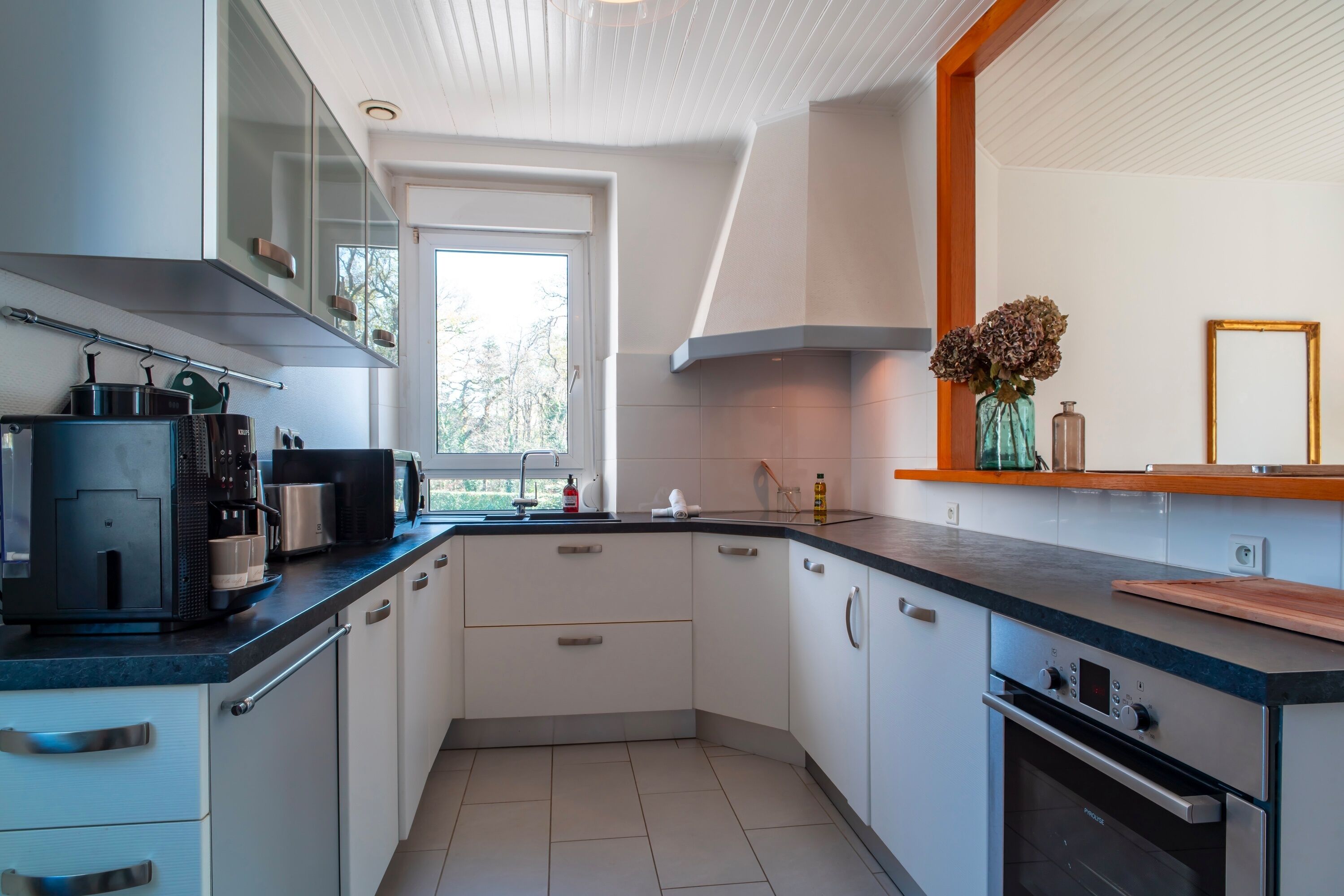 Una cucina moderna con mobili bianchi, un piano di lavoro nero ed elettrodomestici in acciaio inossidabile.