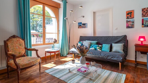 A cozy living room with a sofa, a wooden chair, a coffee table, and a vase with flowers. - Ti an dour, entre terre et mer (Crac'h)