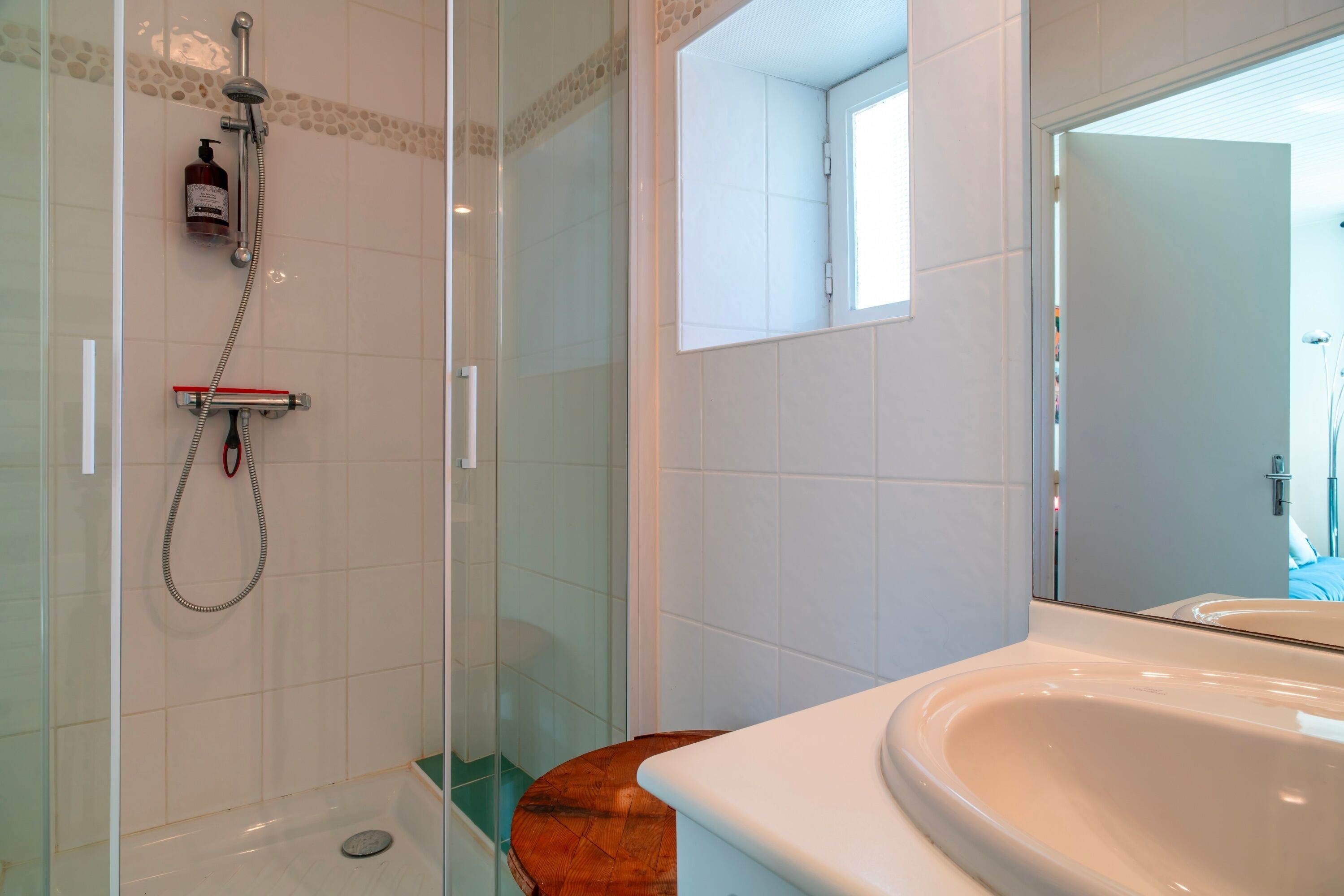 Un baño con ducha de vidrio, tocador de madera y un espejo grande.