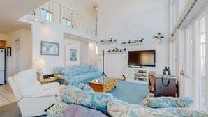 A spacious living room with a high ceiling, a sofa set, a television, and a staircase leading to an upper level. - Charming 4-bedroom house with WiFi and AC in tranquil Ocean Pines (Ocean Pines)